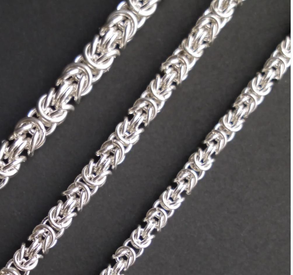 Three intricate silver chains of different sizes are organized diagonally across the frame.